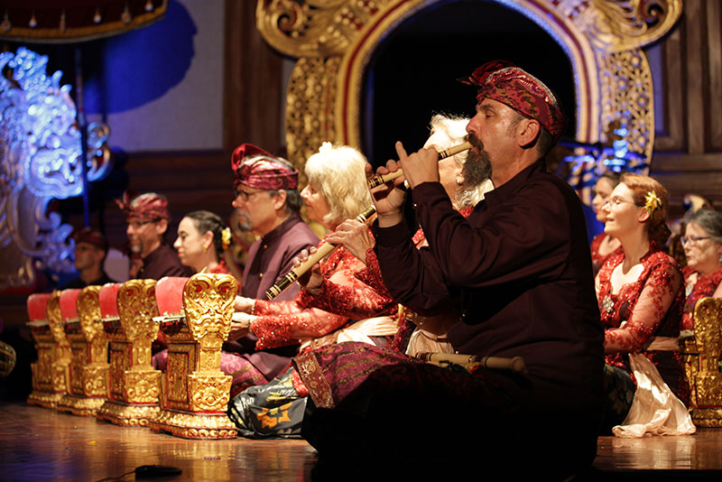 Performers with Gamelan Sekar Jaya seated on a floor, playing traditional Balinese instruments at a concert.