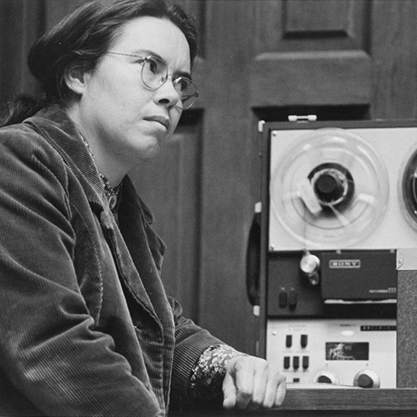 A black and white photograph of Pauline Oliveros seated in the Mills Concert Hall. Photo by 