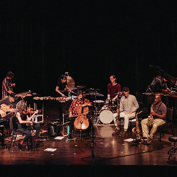 An improvisational ensemble of including keyboards, harp, violin, cello, drum set, saxophone are arrayed across a stage for a Mills Music Now concert in Oakland, California. Photo by Robbie Sweeny.