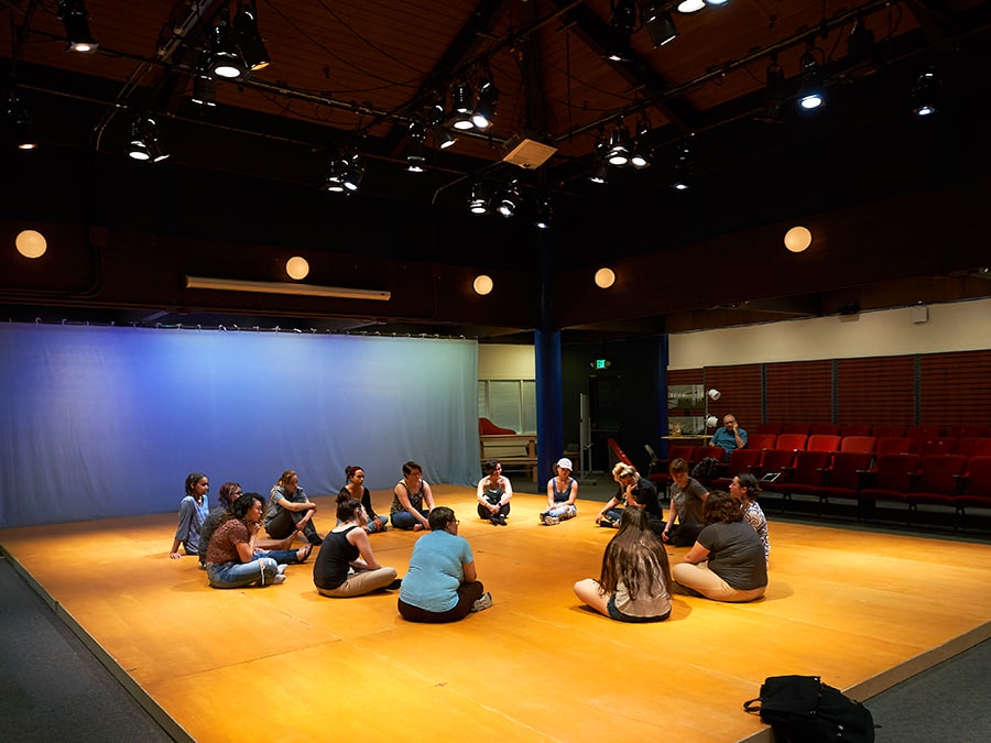 Students sit in a circle on the sprung flooring of the intimate Rothwell Theater on the Mills College campus.